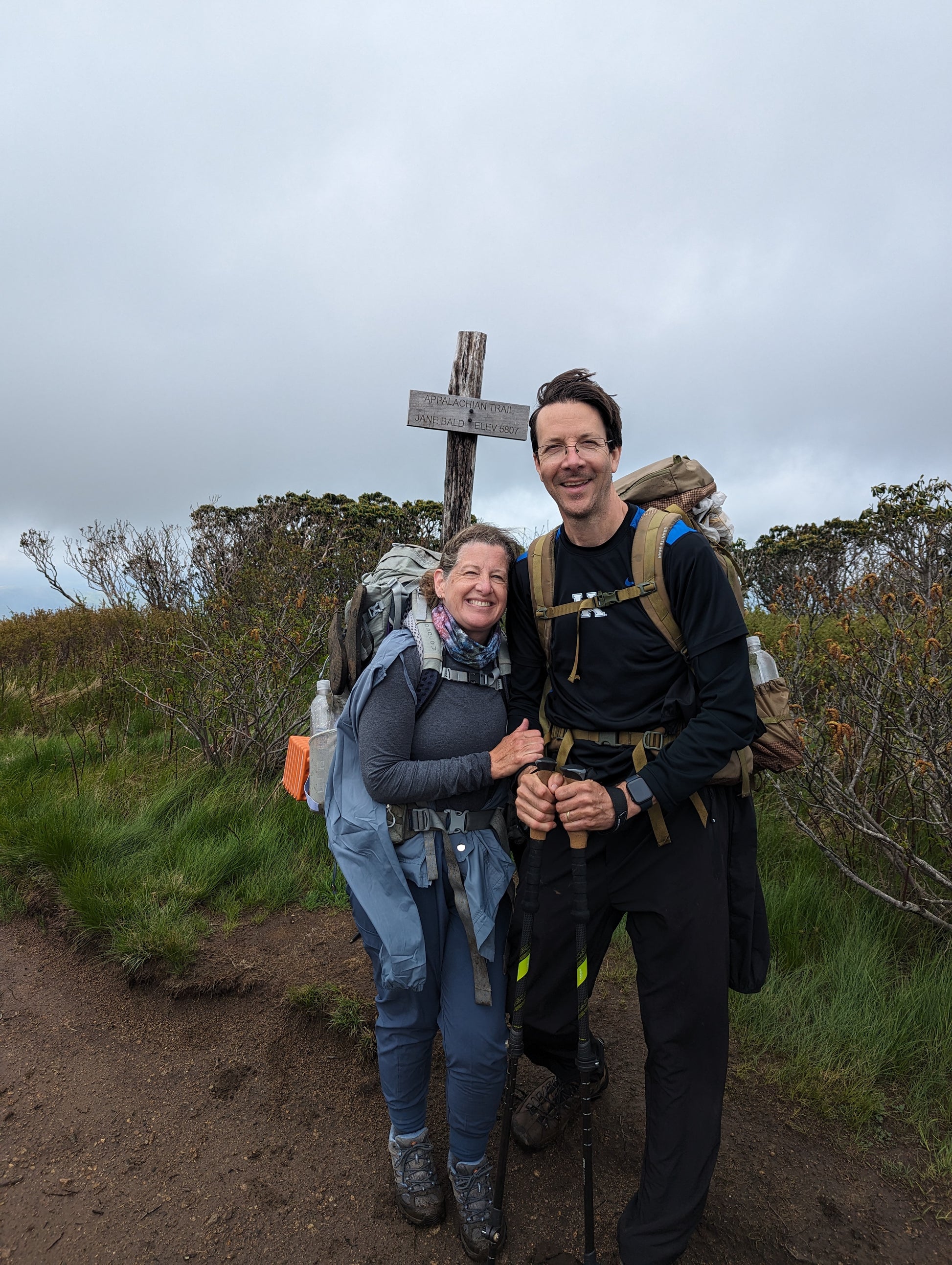 A woman and a man with backpacks standing on a hiking trail