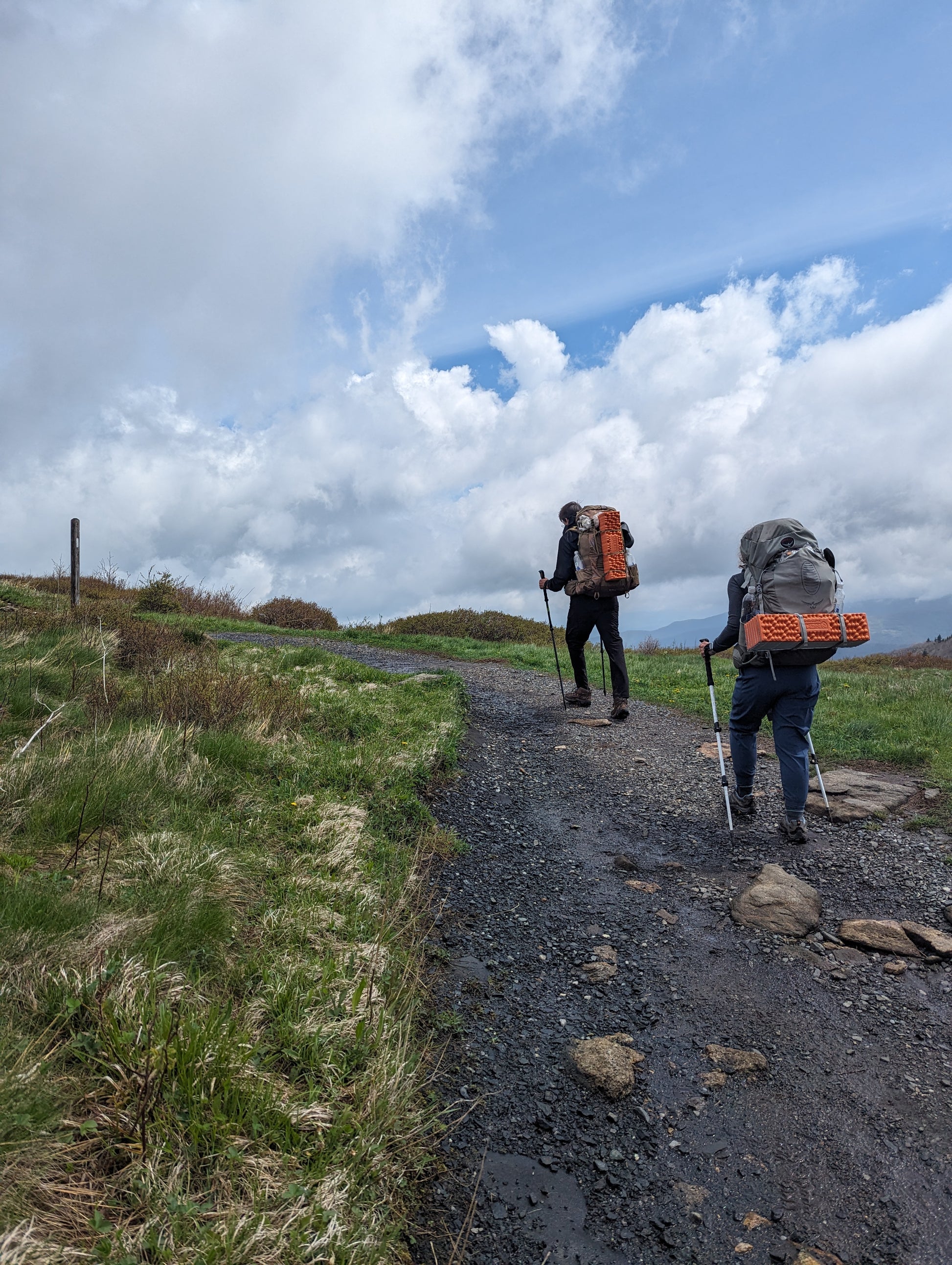 Two backpackers hiking uphill on a trail ahead